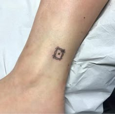 a small tattoo on the ankle of a person with a square shaped object in it