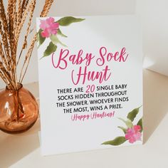 a card that says baby sock hunt next to a vase with pink flowers on it