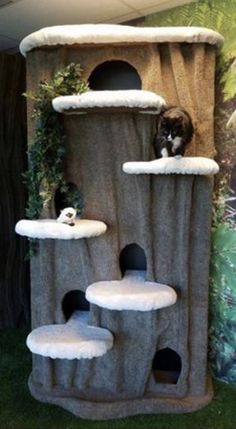 a cat tree in the middle of a room with a mural on the wall behind it