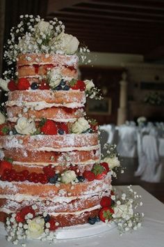 a wedding cake with strawberries and blueberries on the top is covered in powdered sugar