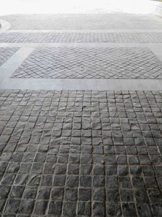 a person with an umbrella is walking down the street in front of some brick pavement