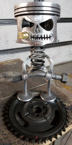 a metal robot sculpture sitting on top of a piece of wood