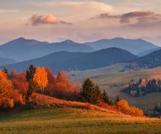 the mountains are covered in autumn foliage and trees with oranges, yellows, and green