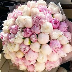 a bouquet of pink and white peonies in the back seat of a car