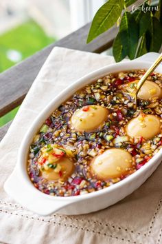 a white bowl filled with food sitting on top of a table next to a potted plant