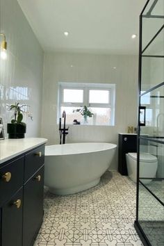 a white bath tub sitting next to a toilet in a bathroom under a window near a sink