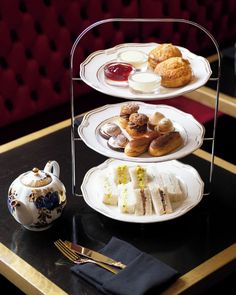 three tiered trays filled with pastries on top of a table next to a teapot