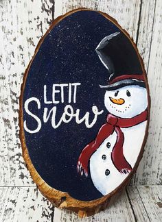 a snowman painted on a piece of wood with the words let it snow written in white