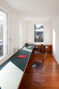 an empty room with two chairs and a desk in front of a window that has a laptop on it