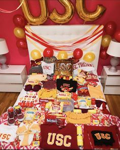 a bed covered in food and balloons next to a sign that says usu on it