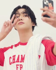 a young man is taking a selfie with his cell phone while wearing a red and white baseball shirt