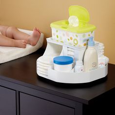 a baby laying on top of a table next to a bottle and diaper dispenser