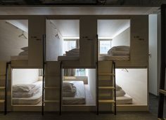 bunk beds are lined up in the middle of a room with white linens on them