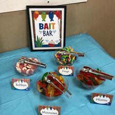 a table topped with lots of different types of gummy bears and bowls filled with candy