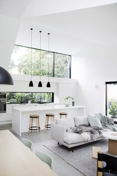 a living room filled with furniture next to a kitchen and dining room table in front of a large window