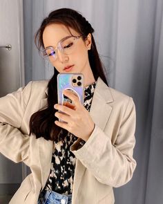 a woman wearing glasses is taking a selfie with her cell phone while standing in front of a mirror