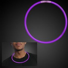 a man wearing a purple necklace and black t - shirt is shown in front of a dark background