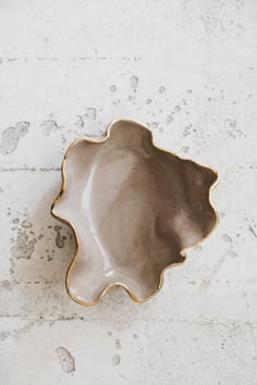 a white and gold plate sitting on top of a cement floor next to a brick wall