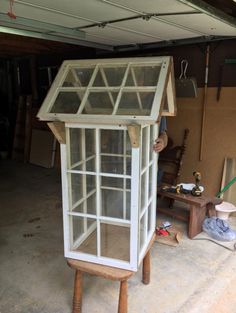 a large white glass case sitting inside of a garage next to a table and chair