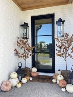 the front door is decorated with pumpkins and gourds as well as lanterns