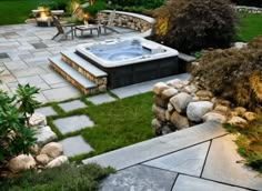 an outdoor hot tub in the middle of a yard with grass and rocks around it