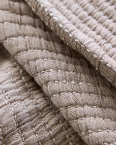 the texture of an upholstered blanket is shown in grey and white colors, with stitchs on it