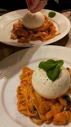 two white plates topped with pasta and an egg sitting on top of them next to each other