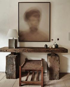 a wooden table sitting next to a painting on the wall