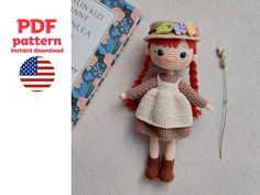 a crocheted doll laying on the ground next to an american flag and a book