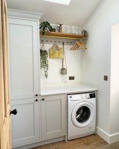 a washer and dryer in a small room with white cupboards on the wall