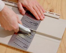 a person using a pair of scissors to cut metal strips on a piece of wood