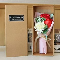 a bouquet of flowers in a box on a table next to books and a book