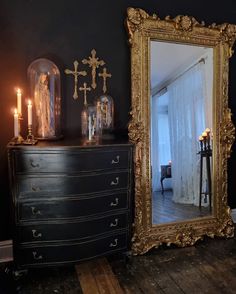 a large mirror sitting on top of a dresser next to a black dresser with candles