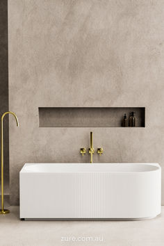 a white bath tub sitting next to a gold faucet