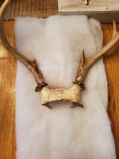 a deer's antlers are laying on a piece of white fur next to a wooden frame