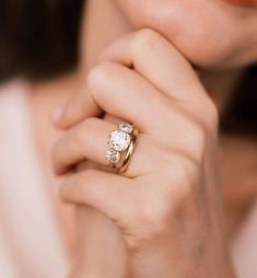 a close up of a person wearing a gold ring with diamonds on the middle and side