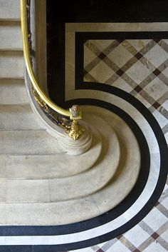 an elegant marble staircase with gold handrails and black and white checkered flooring