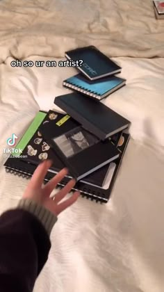 a person reaching for books on a bed