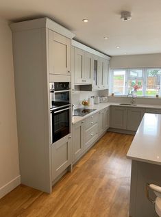 an empty kitchen with white cabinets and wood flooring is pictured in this image, there are no people around