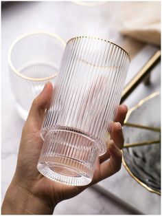 a hand holding a clear glass on top of a table