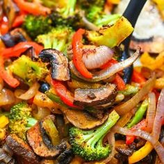 a plate full of stir fry with broccoli, peppers and onions