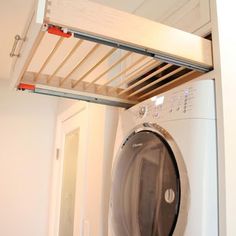 a washer and dryer in a room with a wooden rack above it's door