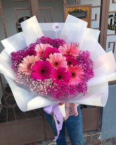 a woman holding a bouquet of pink flowers