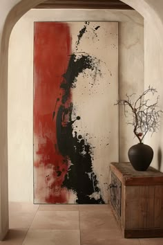 an abstract painting on the wall next to a wooden cabinet and vase with flowers in it