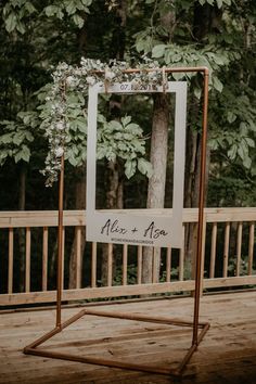 a sign that is on top of a wooden floor in front of trees and bushes