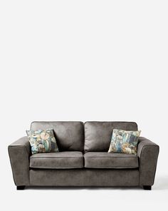 a gray couch with two pillows on it's back and one arm facing the camera