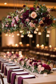 a long table with purple and red flowers hanging from it's centerpieces