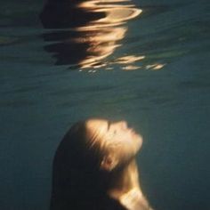 a woman swimming in the water with her head above the water's surface, looking up