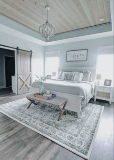 a white bed sitting on top of a wooden floor next to a rug in a bedroom