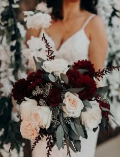 a bride holding a bouquet of red and white flowers